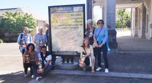 L'équipe AcomArtistes devant l'affiche de l'exposition de Billière
